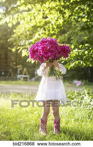 Stock Photo - Girl holding bouquet of flowers in backyard. Fotosearch