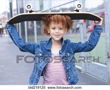 Stock Photography - Girl holding skateboard in urban park. Fotosearch