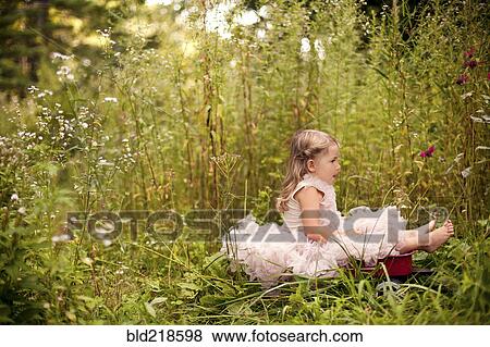 Stock Photo - Girl in frilly dress sitting in tall flowers. Fotosearch