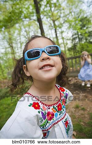 Stock Photograph - Girl in sunglasses standing outdoors. Fotosearch