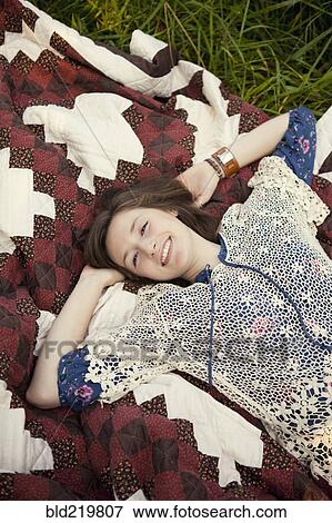 Stock Photo - Girl laying on blanket in grass. Fotosearch