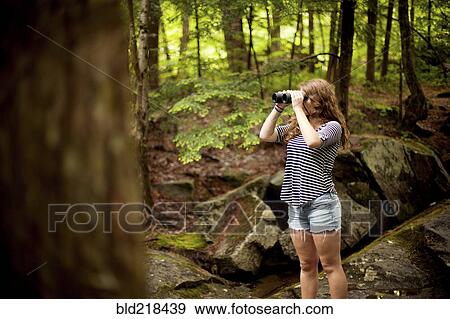 Stock Photo - Girl looking through binoculars in forest. Fotosearch