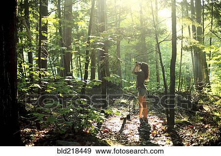 Stock Photo - Girl looking through binoculars in forest. Fotosearch