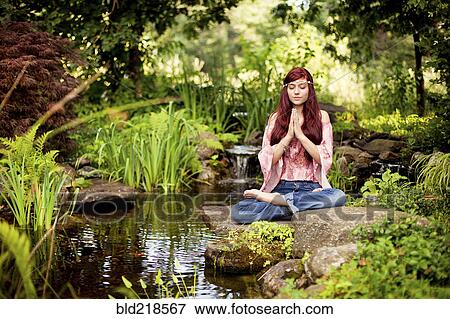 Stock Photo - Girl meditating near rural creek. Fotosearch