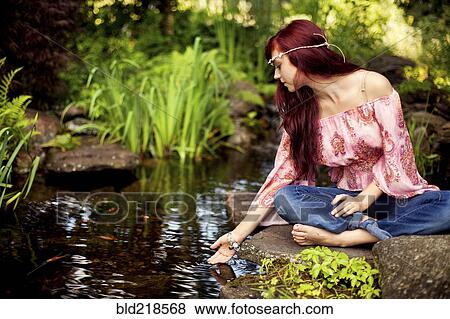 Stock Photo - Girl meditating near rural creek. Fotosearch