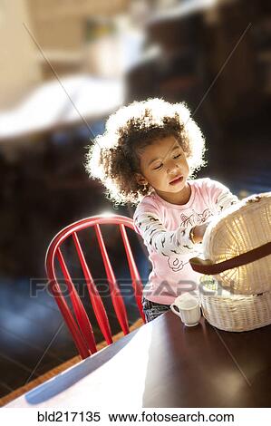 Stock Photography - Girl opening basket at table. Fotosearch