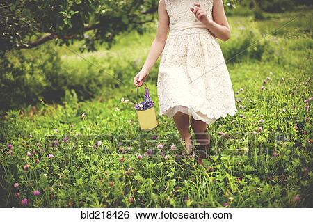 Stock Photograph - Girl picking flowers in rural field. Fotosearch