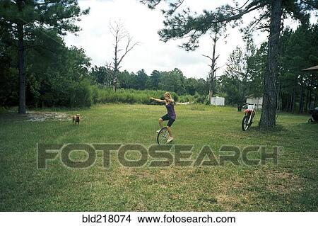 Picture - Girl playing on unicycle in field. Fotosearch