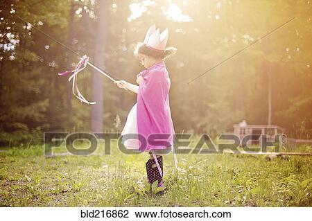 Stock Image - Girl playing princess in backyard. Fotosearch