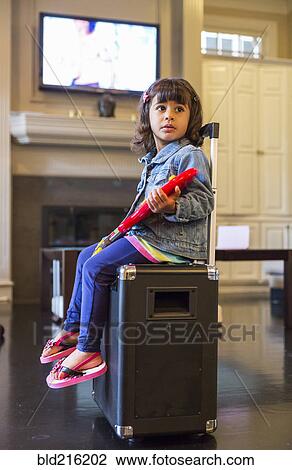 Stock Image - Girl playing toy guitar on amplifier in living room. Fotosearch