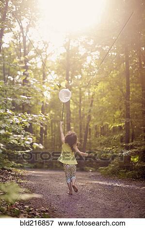 Stock Photo - Girl playing with butterfly net in forest. Fotosearch