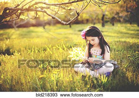 Stock Image - Girl playing with pinwheel in rural field. Fotosearch
