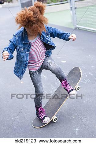 Stock Image - Girl playing with skateboard in urban park. Fotosearch
