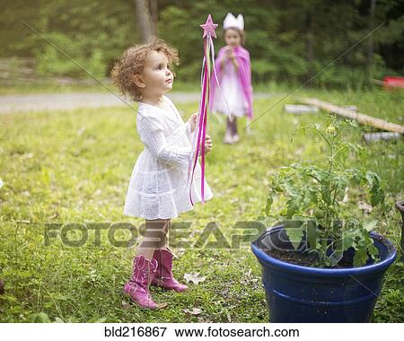 Stock Photo - Girl playing with wand in backyard garden. Fotosearch