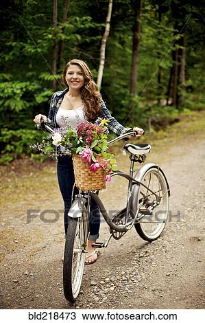 Stock Image - Girl pushing bicycle on dirt path. Fotosearch