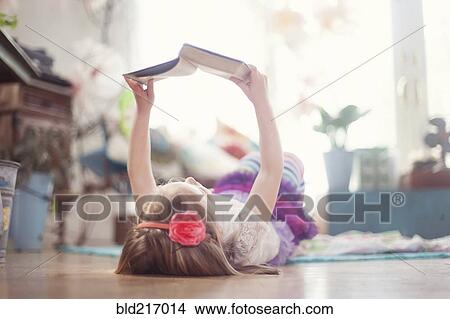 Girl reading book on living room floor View Large Photo Image Picture - Girl reading book on living room floor. Fotosearch