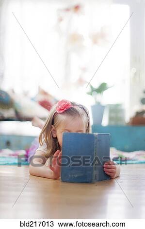 Girl reading book on living room floor View Large Photo Image Stock Image - Girl reading book on living room floor. Fotosearch