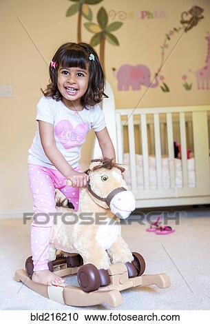 Girl riding rocking horse in nursery View Large Photo Image Stock Image - Girl riding rocking horse in nursery. Fotosearch