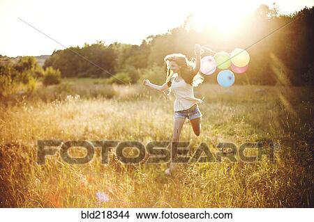 Girl running with balloons in sunny field View Large Photo Image Picture - Girl running with balloons in sunny field. Fotosearch