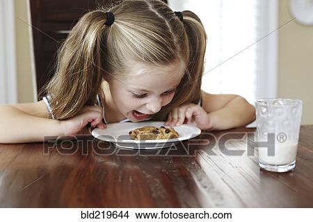 Picture - Girl shouting at cookie on table. Fotosearch