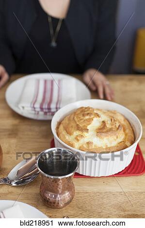 Stock Image - Girl sitting near baked souffle on table. Fotosearch