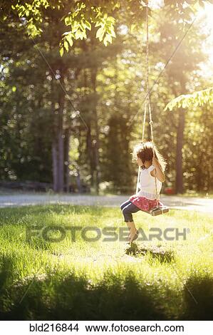 Picture - Girl sitting on swing in field. Fotosearch
