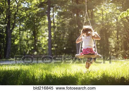 Stock Photography - Girl sitting on swing in field. Fotosearch