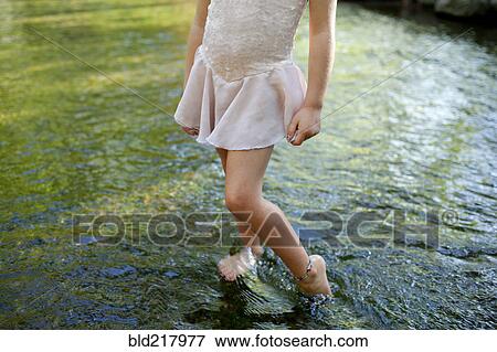 Stock Photo - Girl standing barefoot in pond. Fotosearch