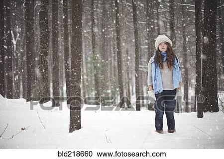 Stock Image - Girl standing in snowy forest. Fotosearch