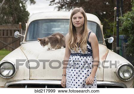 Stock Photo - Girl standing near cat on vintage car. Fotosearch