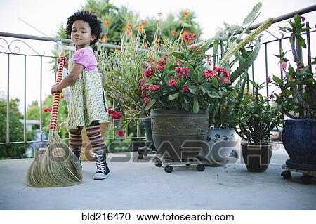 Stock Image - Girl sweeping patio with broom. Fotosearch