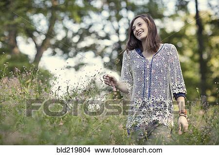 Picture - Girl walking in tall grass in forest. Fotosearch