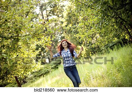 Stock Image - Girl walking in tall grass in rural field. Fotosearch