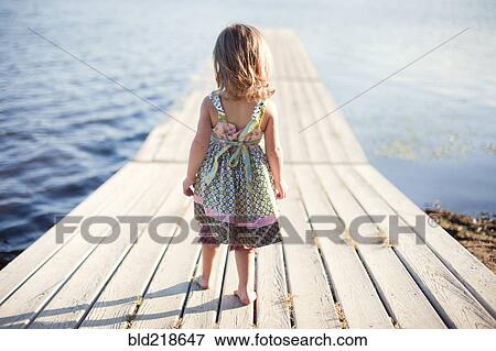 Girl walking on wooden dock over rural lake View Large Photo Image Stock Photo - Girl walking on wooden dock over rural lake. Fotosearch