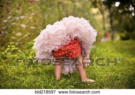 Girl wearing frilly dress in garden View Large Photo Image Stock Photo - Girl wearing frilly dress in garden. Fotosearch