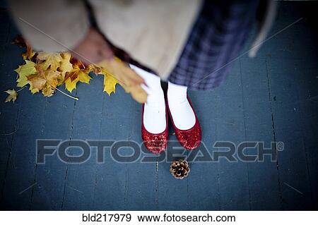 Stock Photo - Girl wearing red slippers near pinecone. Fotosearch