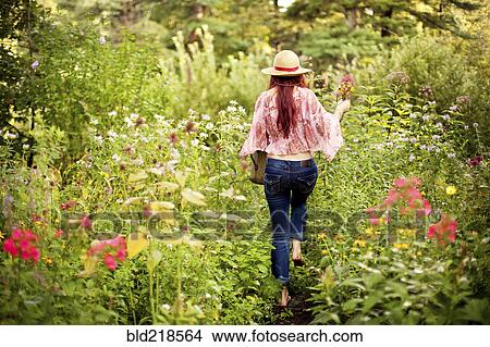 Picture - Girl wearing straw hat in garden. Fotosearch