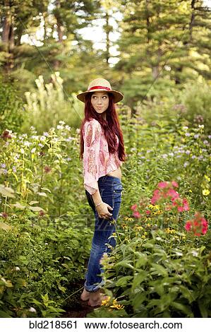 Stock Image - Girl wearing straw hat in garden. Fotosearch