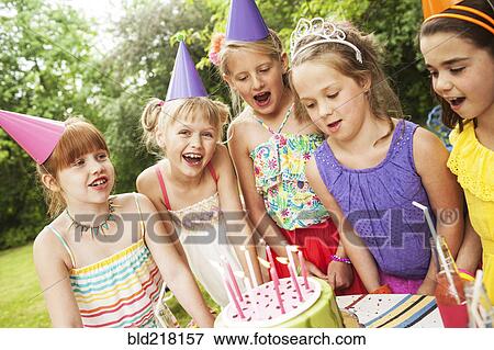 Stock Photo - Girls admiring cake at birthday party outdoors. Fotosearch
