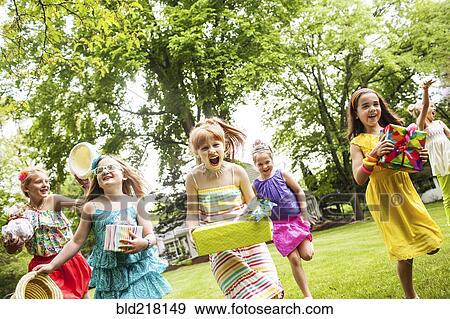 Girls carrying gifts at birthday party View Large Photo Image Stock Photo - Girls carrying gifts at birthday party. Fotosearch