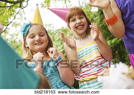 Stock Image - Girls clapping at birthday party outdoors. Fotosearch