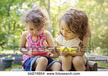 Picture - Girls examining caterpillar with magnifying glass. Fotosearch