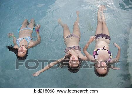 Girls floating in swimming pool View Large Photo Image Stock Photo - Girls floating in swimming pool. Fotosearch