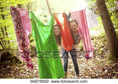 Girls hiding behind clothesline laundry in forest View Large Photo Image Stock Image - Girls hiding behind clothesline laundry in forest. Fotosearch