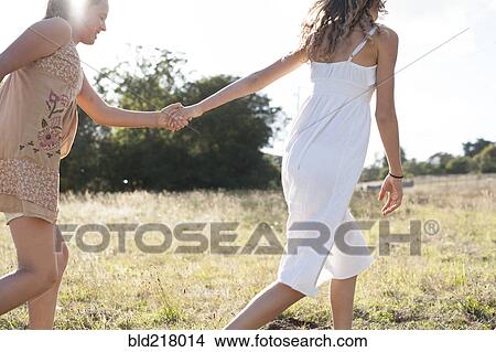 Girls holding hands in field View Large Photo Image Picture - Girls holding hands in field. Fotosearch
