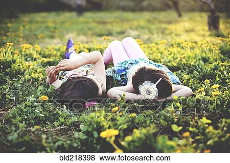 Stock Photo - Girls talking and laying in field of flowers. Fotosearch