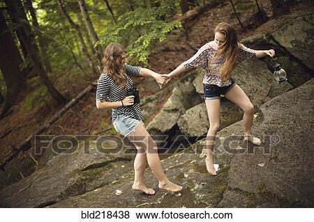 Stock Photo - Girls walking barefoot on boulder in forest. Fotosearch