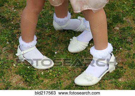 Stock Image - Girls wearing dress shoes and socks in grass. Fotosearch