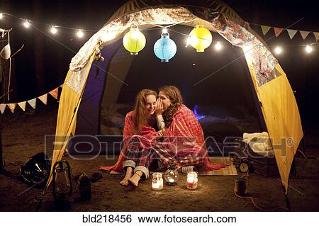 Stock Photograph - Girls whispering in camping tent at night. Fotosearch