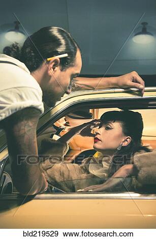 Stock Photo - Glamorous couple talking in vintage car. Fotosearch